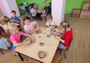 Dzieci przy stoliku pakują swoje czekoladowe serca w celofan